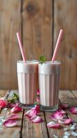 Refreshing milkshakes served in tall glasses with pink straws surrounded by rose petals photo