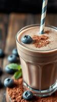 Rich chocolate smoothie with blueberries and mint served in a clear glass on a wooden table photo