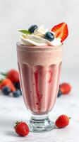 Refreshing strawberry and blueberry milkshake topped with cream and fruits photo