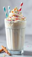 Delicious milkshake topped with whipped cream and colorful sprinkles in a clear glass photo