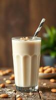 Creamy almond milkshake served in a tall glass with a striped straw and garnished with nuts on a rustic wooden table photo