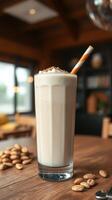 Creamy milkshake in a tall glass served with a striped straw and coffee beans on the table photo