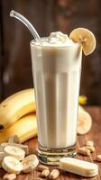Delicious banana smoothie with whipped cream and slices, served in a tall glass on a rustic wooden table photo