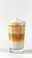 Creamy layered beverage with caramel drizzle served in a clear glass on a plain background photo