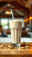 Creamy nut beverage served in tall glass with striped straw and nuts on wooden table in cozy setting photo