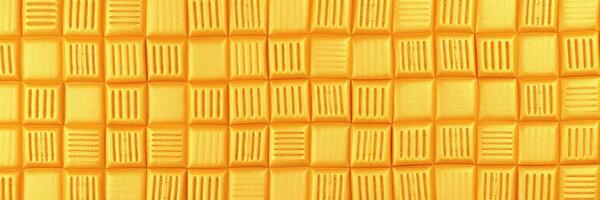 Bright yellow textured surface resembling a checkerboard pattern created with clay or similar material photo