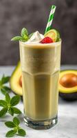 Refreshing avocado smoothie topped with cream, garnished with mint and fruit in a glass photo