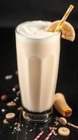 Creamy banana smoothie prepared with fresh ingredients, garnished with a banana slice and a striped straw photo