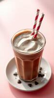 Creamy chocolate milkshake served in a tall glass with striped straws and chocolate chips on a plate photo