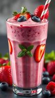 Refreshing berry smoothie with strawberries and blueberries garnished with mint leaves in a tall glass photo