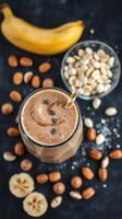 Delicious chocolate banana smoothie with nuts and toppings prepared on a dark countertop photo