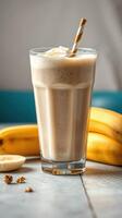 Creamy banana smoothie served in a tall glass with striped straw and fresh bananas in the background photo