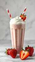 Refreshing strawberry milkshake topped with whipped cream and fresh strawberries in a glass cup photo