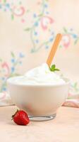 Creamy whipped cream served in a bowl with fresh strawberry and mint garnish on a floral background photo