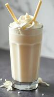 Creamy vanilla shake topped with whipped cream served in a tall glass at a cozy cafe photo