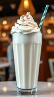 Delicious milkshake topped with whipped cream and colorful sprinkles served in a tall glass at a cafe photo