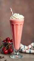 Creamy cherry milkshake served in a tall glass with whipped cream and a straw on a wooden table photo
