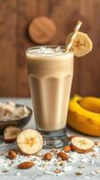 Creamy banana smoothie with coconut and almonds served in a tall glass on a wooden table photo