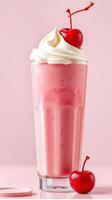 Refreshing pink milkshake topped with whipped cream and cherry on a pastel background photo