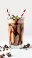 Creamy chocolate milkshake garnished with mint and served in a tall glass with striped straws photo
