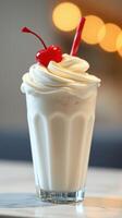 Creamy milkshake with whipped cream and cherry served in a tall glass at a cozy diner photo