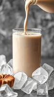 Creamy beverage is being poured into a glass surrounded by ice cubes on a cool surface photo