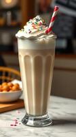 Delicious milkshake topped with whipped cream and colorful sprinkles served in a tall glass with a striped straw photo