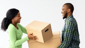 Happy Young Black Spouses Moving To New Apartment, Carrying Belongings In Cardboard Boxes And Smiling To Each Other, African American Couple Enjoying Relocation To Their Own Flat, Free Space photo