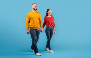 A married couple walks hand-in-hand, radiating love and affection. Dressed in casual attire, they share smiles and warmth against a bright blue backdrop, reflecting their bond, copy space photo
