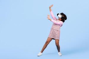 A joyful preteen girl engages with virtual reality, appearing immersed in her surroundings. She wears a VR headset and shows excitement while playing, copy space photo
