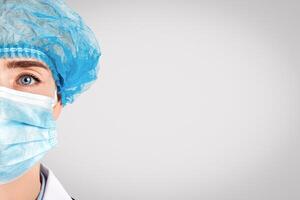 Therapist in a protective mask and hat and stethoscope on light background photo