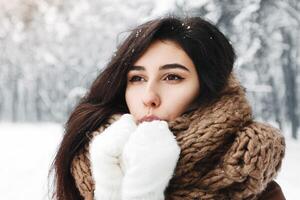 Cold Winter. Dreamy Girl Blowing On Hands In Gloves Trying To Warm Up Standing In Snowy Forest photo