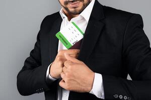 Cropped of entrepreneur in formal attire is placing a business card into his suit pocket. The environment is a studio, emphasizing his professional lifestyle as a millennial manager. photo