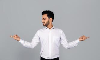 A Middle Eastern businessman stands confidently in a studio environment, gesturing with both hands. He radiates professionalism and youthful energy, embodying a modern entrepreneurial spirit. photo