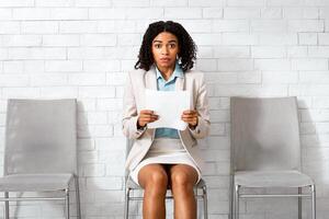 Attrative black girl with resume being afraid of her employment interview in office. Space for text. Panorama photo