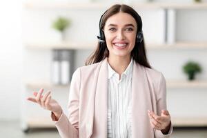 Portrait Of Hotline Operator Lady Wearing Headset Smiling And Talking Looking At Camera Standing In Modern Office. Call, Online Consultation With Professional Consultant Or Manager Concept photo