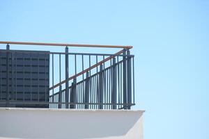 A modern balcony railing stands out vividly against a clear blue sky photo