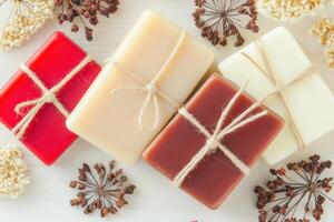 Artisan soaps in rich hues tied with twine and accented by delicate dried flowers on a neutral surface photo