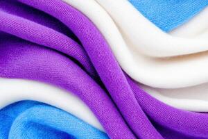 Close-up view of dark blue velvet fabric elegantly draped with a soft white and lavender scarf showcasing gentle folds and reflections photo