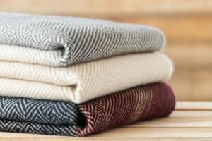 Cozy woolen blankets stacked neatly on a rustic wooden bench for warmth and comfort in a serene indoor setting during a peaceful afternoon photo