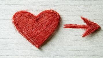 Artistic representation of a red heart and arrow on textured white paper creating a unique design photo