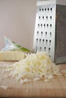 Freshly Grated Cheese Being Prepared with a Grater on a Cutting Board photo