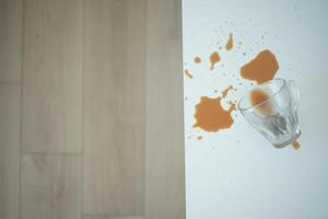 A drink was accidentally spilled on a desk with a laptop and glasses, creating a mess photo