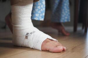 An injured foot wrapped in a bandage is gently resting on the floor, awaiting care and healing photo