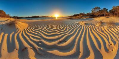 A sand dune at sunset with the sun setting behind it photo