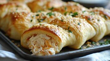 Delicious puff pastry rolls with chicken and cheese filling baking on a tray photo