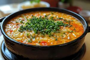 Hot moqueca capixaba fish stew simmering in a clay pot, garnished with chopped chives photo