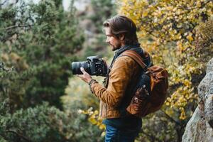 Photographer captures autumn landscape in forest during golden hour with camera and backpack photo