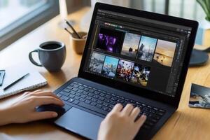 Person editing photos on a laptop at a bright workspace with coffee and notepad