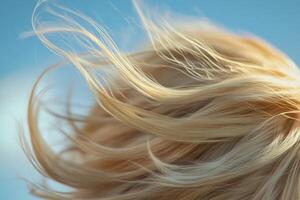 Woman with flowing blonde hair against a clear blue sky enjoying a breezy day outdoors photo